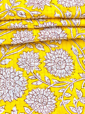 White botanical flowers and leafy vines on mustard yellow quilted fabric.