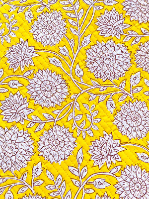 Mustard yellow quilted fabric with white floral print and burgundy outlines.
