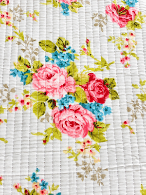 Ivory quilted fabric featuring pink roses, blue flowers, and sage green foliage.