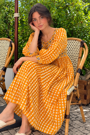 Full-length orange gingham dress styled with neutral sandals