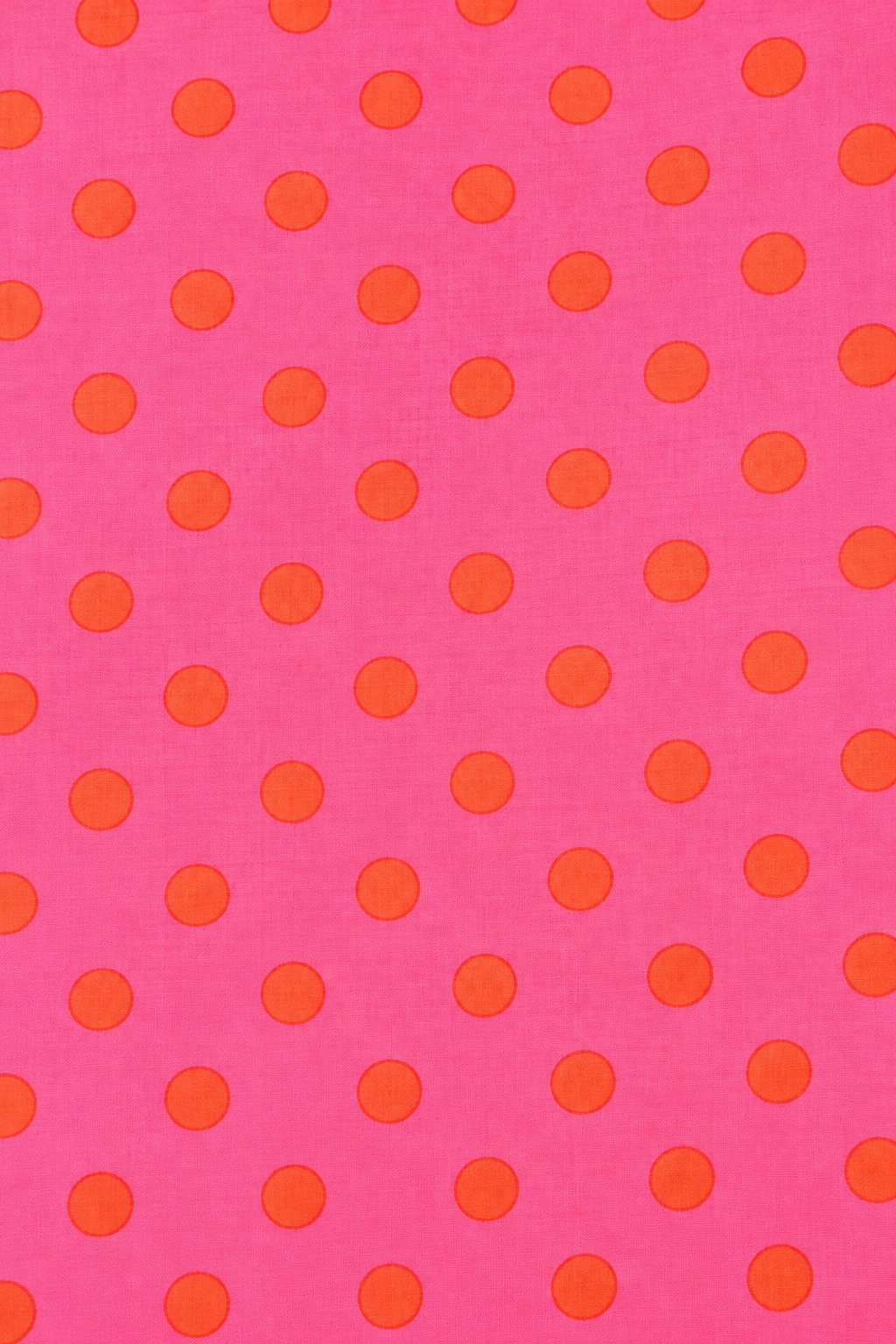 Folded hot pink fabric featuring a bold orange circular dot pattern