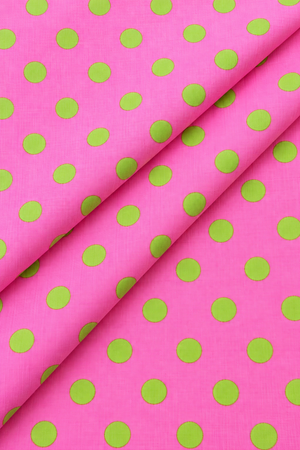 Green polka dot pattern on bright pink fabric