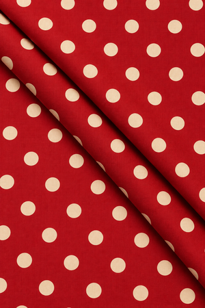 Close-up of cream polka dots on rich maroon dressmaking fabric