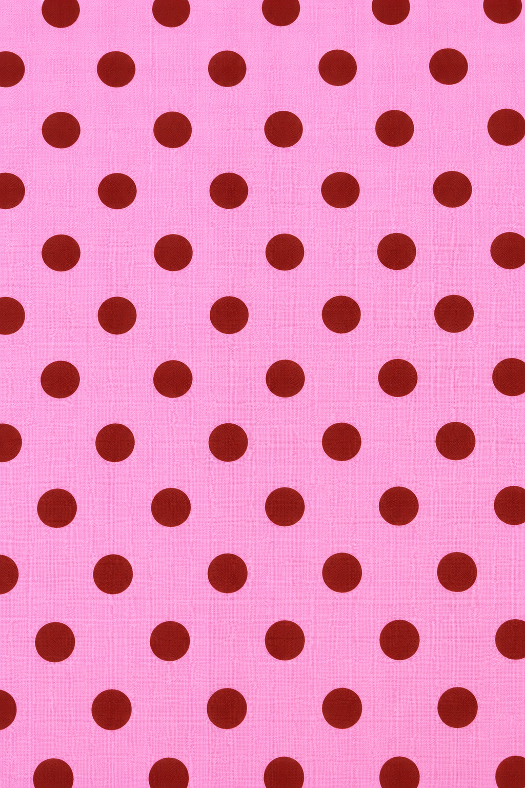 Pink cotton-look fabric featuring evenly spaced red round dots