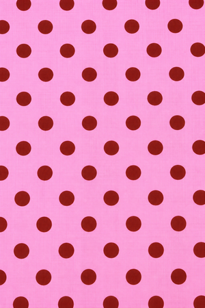 Pink cotton-look fabric featuring evenly spaced red round dots