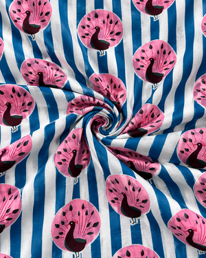 Folded blue and white cotton textile with colorful pink peacock pattern