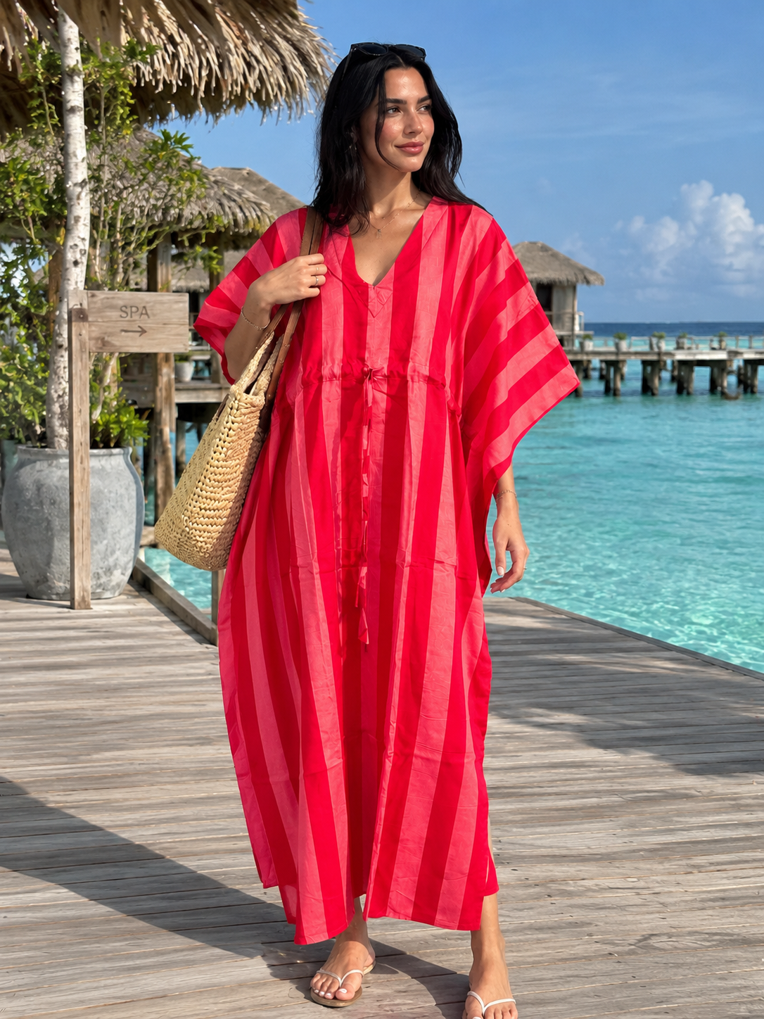 Pink striped cotton kaftan dress worn by a woman at a tropical resort