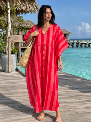 Pink striped cotton kaftan dress worn by a woman at a tropical resort