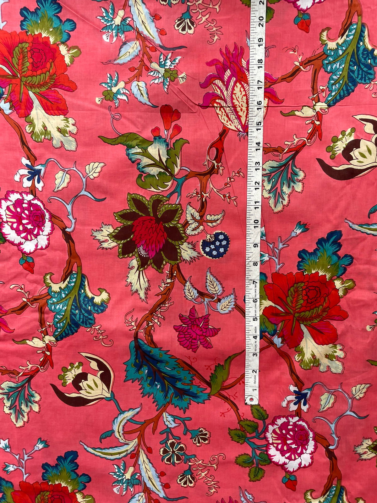 Vibrant pink cotton fabric with colorful flowers and vines
