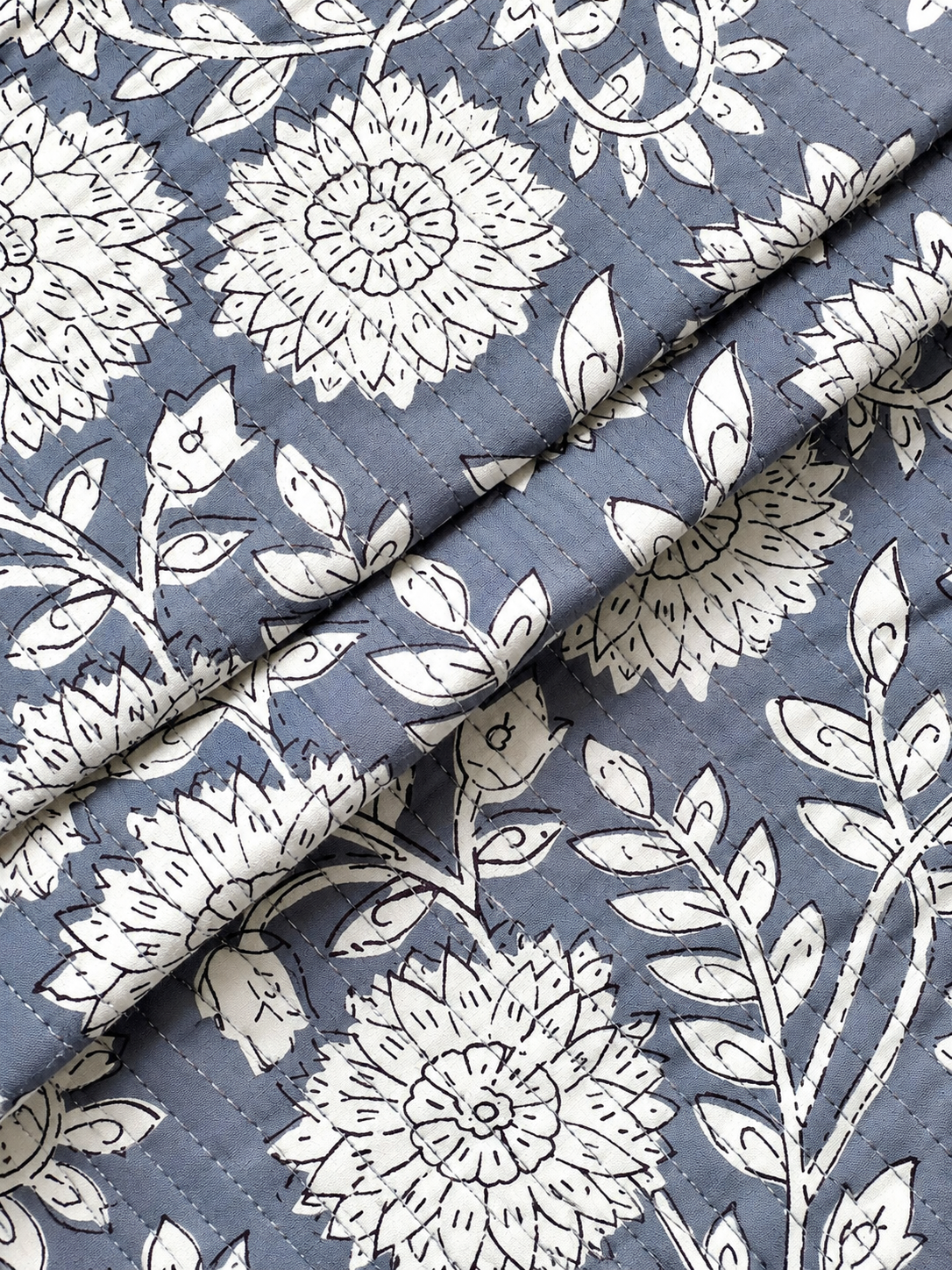 White botanical flowers and leafy vines printed on grey quilted fabric.