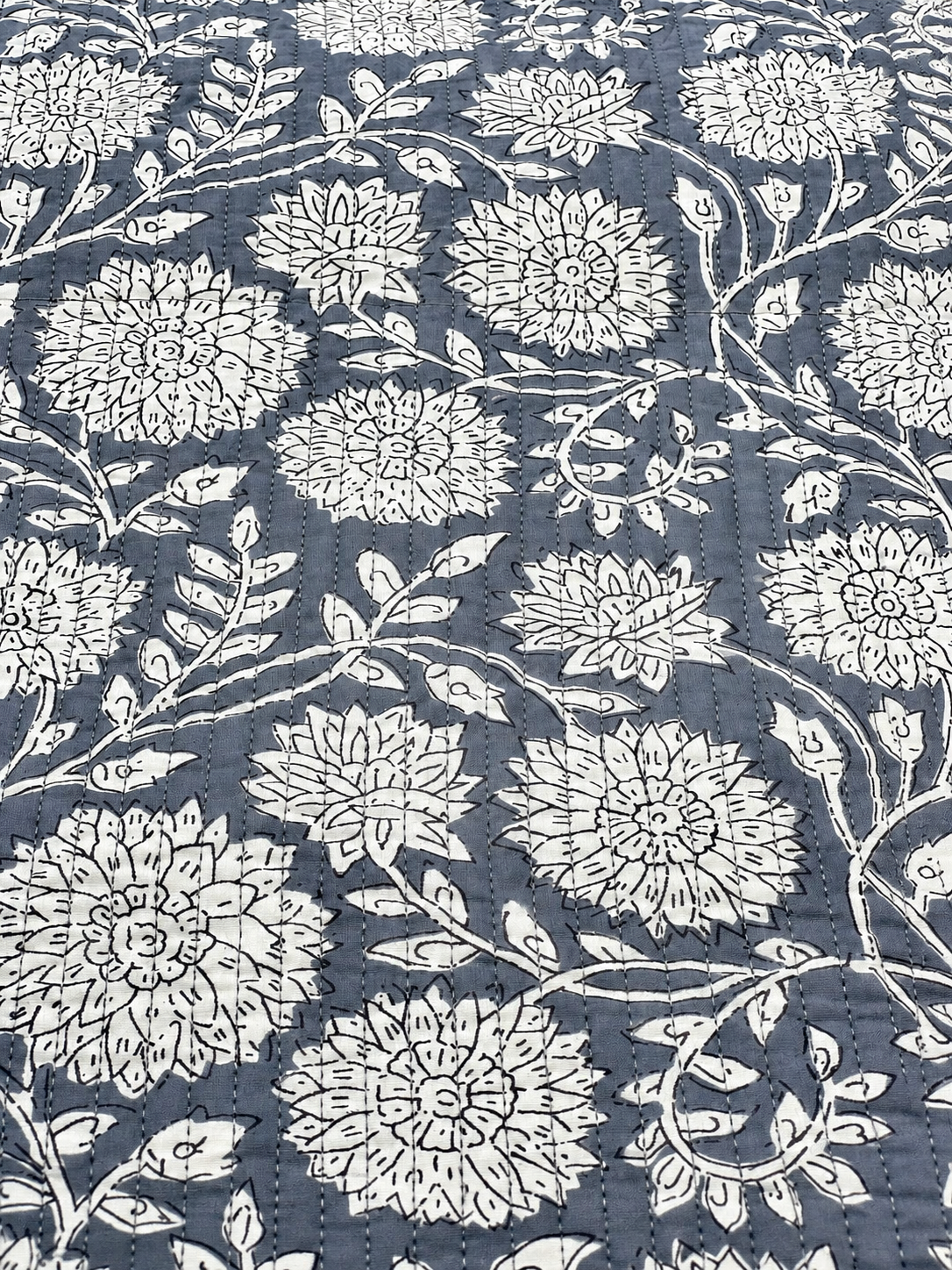Grey floral quilted fabric with white flowers and black botanical outlines.