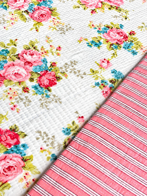 Close-up of pink floral quilted fabric showing stitched texture and rose print.