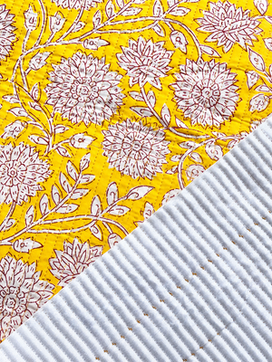 Close-up of yellow floral quilted fabric showing stitched texture.