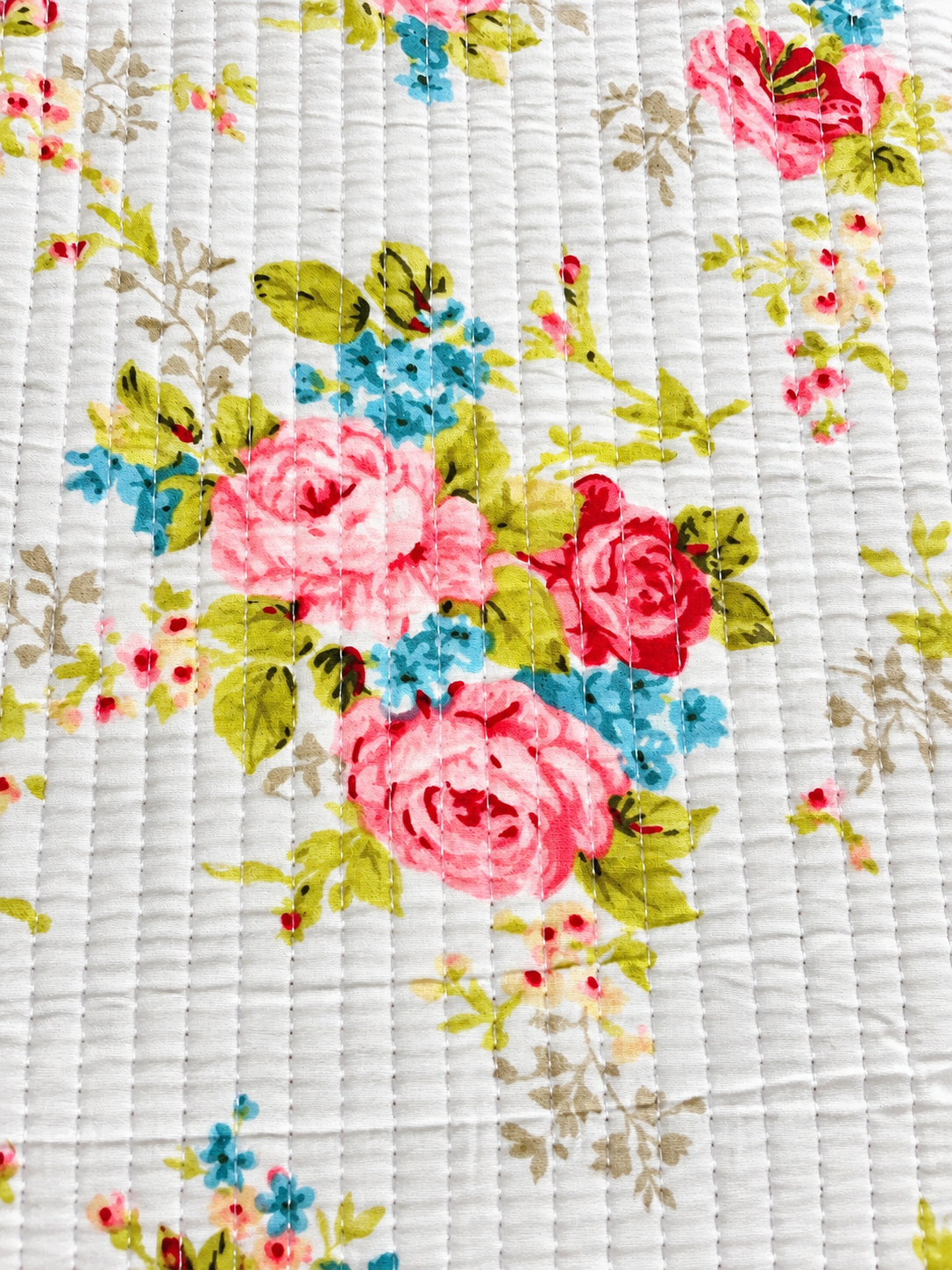Ivory quilted fabric featuring pink roses, blue flowers, and sage green foliage.