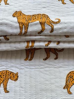 Golden yellow leopard pattern with black outlines on textured quilted fabric.