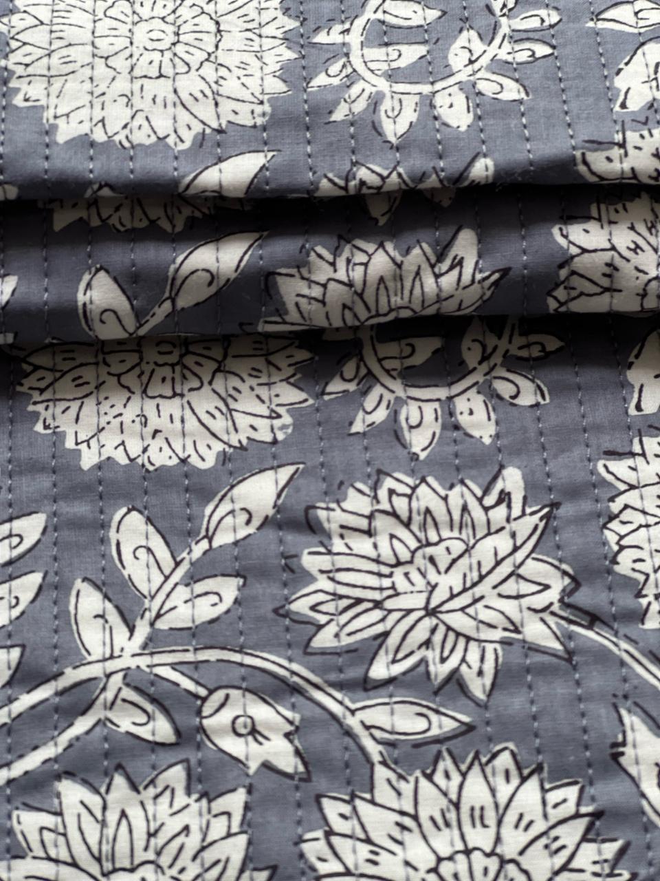 Grey and white floral quilting material with visible stitched lines.